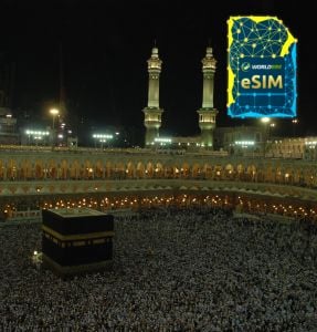  The Grand Mosque in Mecca filled with pilgrims performing Hajj, highlighted by the WorldSIM logo and an image of a WorldSIM eSIM card